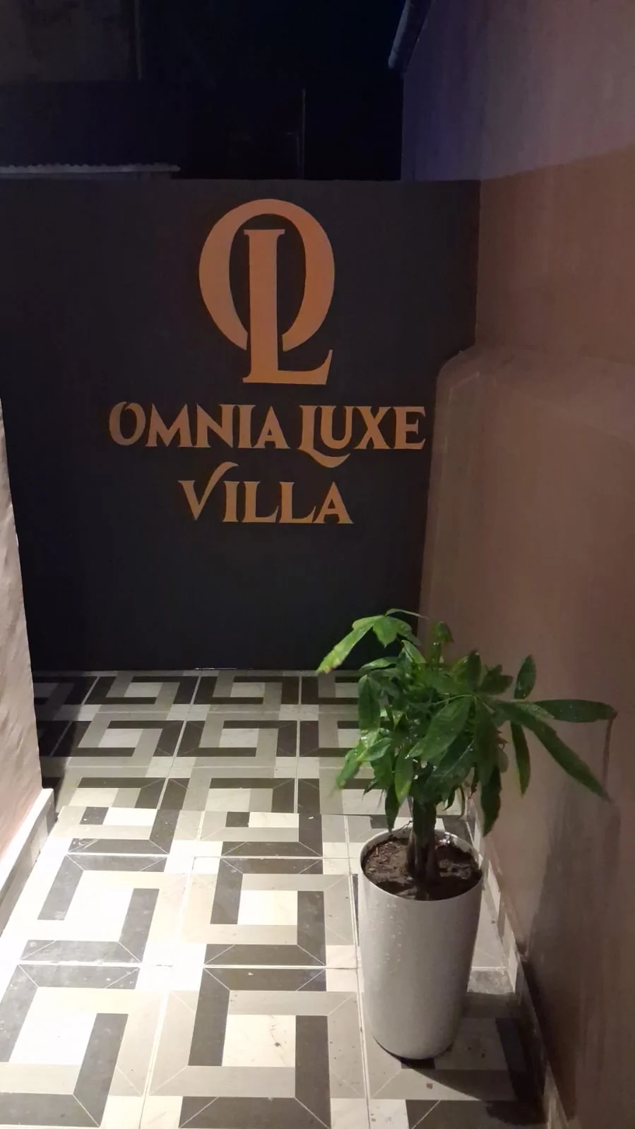 Back-lit Omnia Luxe Villa entrance sign with geometric tilework